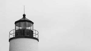 Close-up of a lighthouse lantern room with glass panels and metal railing, symbolizing navigation and timeless guidance